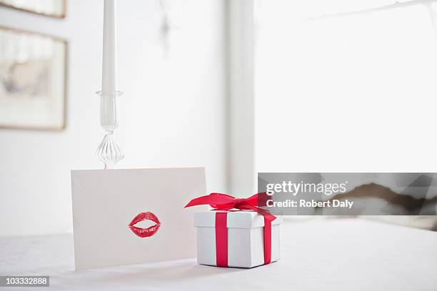 geschenkbox mit schleife und karte mit lippenstift-kuss auf schreibtisch - gift box tag stock-fotos und bilder