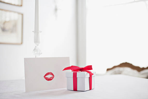 Gift box with ribbon and card with lipstick kiss on desk