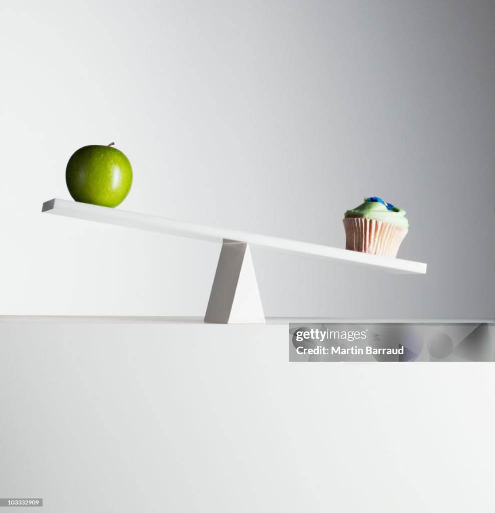 Cupcake tipping seesaw with green apple on opposite end