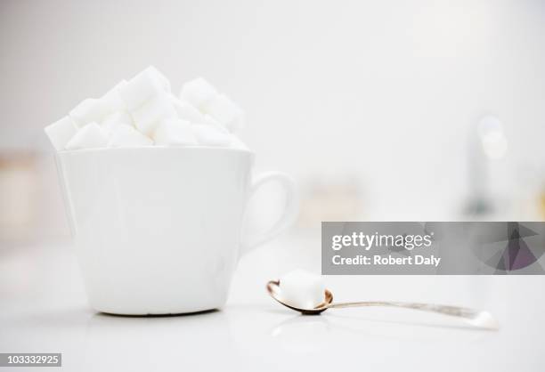 sugar cubes filling coffee cup next to spoon with sugar cube - excess sugar stock pictures, royalty-free photos & images