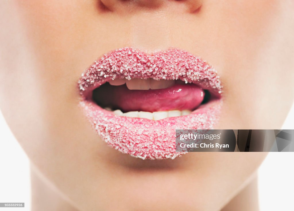 Close up of woman with pink lipstick licking sugar covered lips