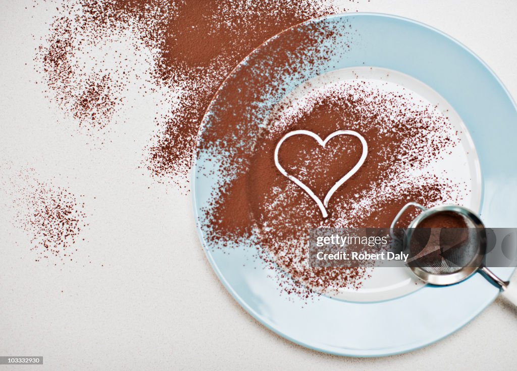 Heart-shape drawn into cocoa powder on plate