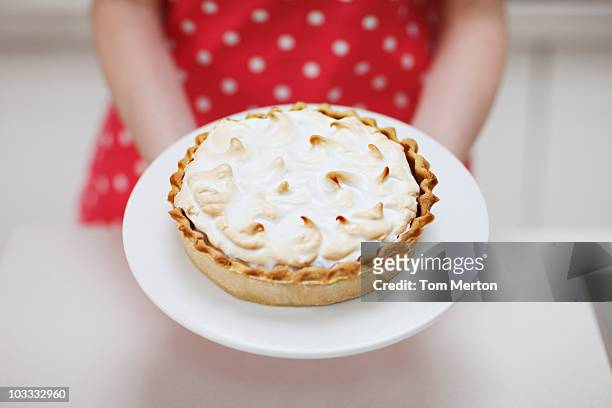 frau holding lemon meringue pie - dessertpasteten stock-fotos und bilder