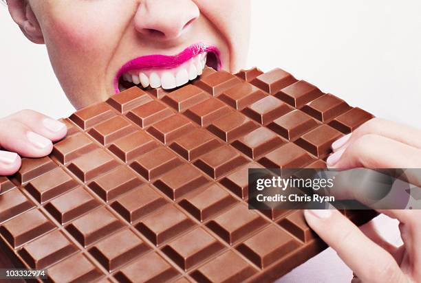 女性のピンクの口紅を噛む大きなチョコレートバー - chocolate eating ストックフォトと画像