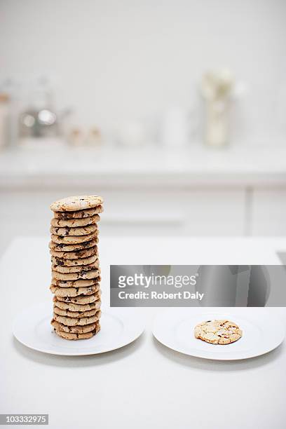stack of cookies on plate next to single cookie on plate - uneven stock pictures, royalty-free photos & images