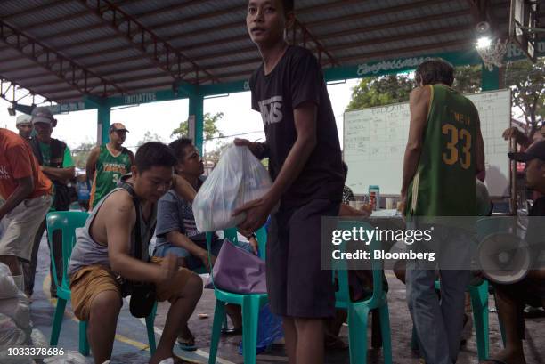 Local government employees distribute relief supplies at a temporary evacuation center at Balzain East Multi Purpose Center ahead of Typhoon...