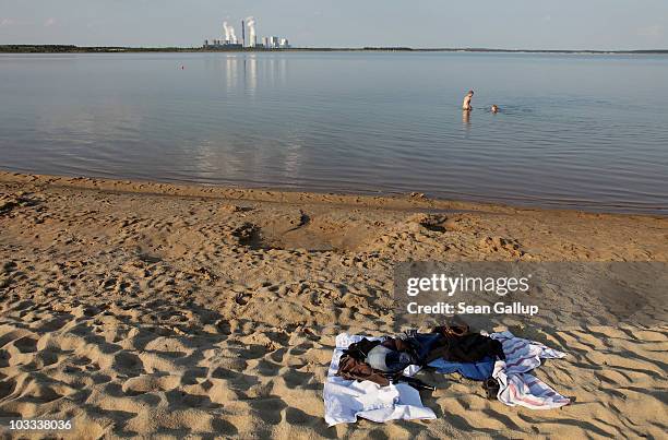 Two young bathers enjoy the water at Baerwalder See lake as exhaust rises from the Boxberg coal-burning power plant behind on August 10, 2010 near...