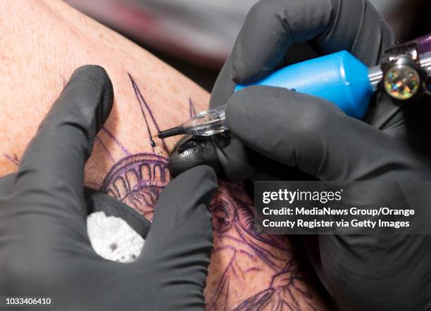 Mark Anthony left, of Mission Viejo, who is a firefighter in San Bernadino, gets a Statue of Liberty tattoo by artist Alexis Vaatete of Vatican...