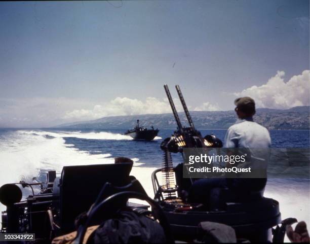 View from the deck of one PT boat as it, and another, patrol the waters of Polloc Harbor, Romblon, Philippines, April 17, 1945. The gunner sits...