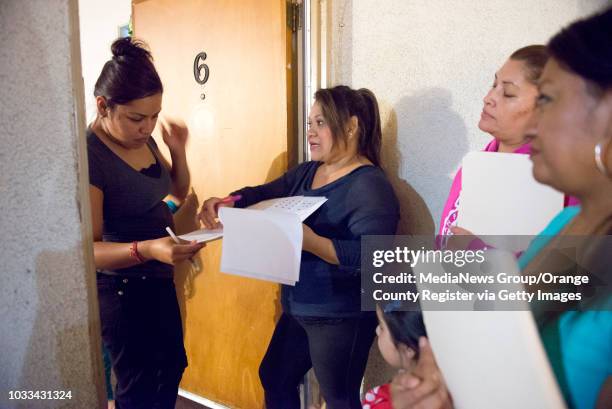 Palm Lane Elementary parent, Magdalena Romero, center, speaks to Yesenia Padilla, left, about signing the petition to convert Palm Lane Elementary...