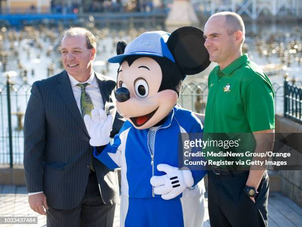 Rival head football coaches Jimbo Fisher with Florida State, at left, and Mark Helfrich with University of Oregon,meet Mickey Mouse during a press...