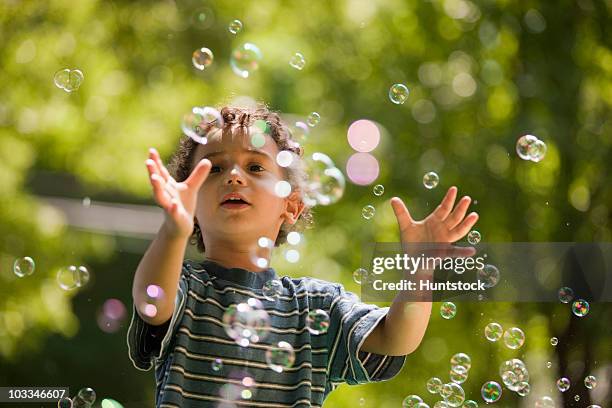 hispanic boy playing with bubbles - catching bubbles stock pictures, royalty-free photos & images