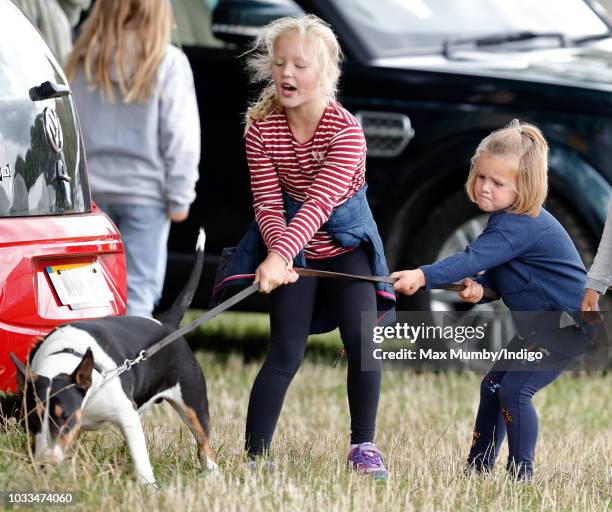 Savannah Phillips and Mia Tindall struggle to control their grandmother's bull terrier dog as they attend the Whatley Manor Horse Trials at Gatcombe...