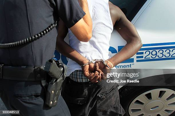 City of Miami police officer, Eldys Diaz, prepares to place a handcuffed person into the back of his patrol car while patrolling the streets on...