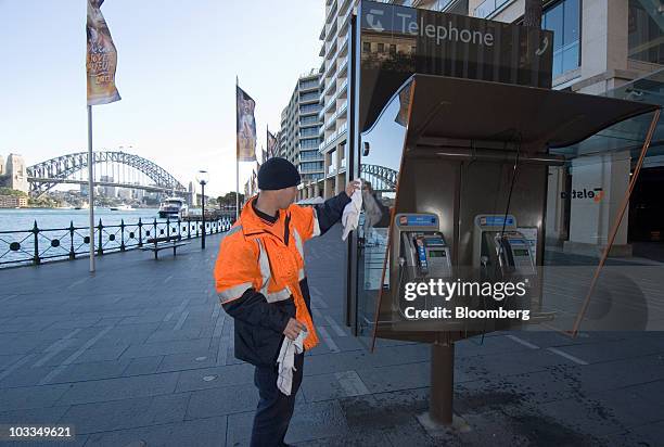 Worker cleans a Telstra Corp. Public phone booth in Circular Quay, Sydney, Australia, on Thursday, Aug. 12, 2010. Telstra Corp., Australia's largest...