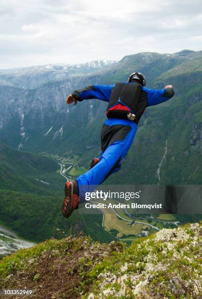 base jumper leaping from cliff in norway - base jumping stock pictures, royalty-free photos & images