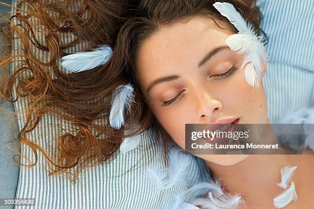 young woman sleeping with white feathers on her - dreams photos et images de collection