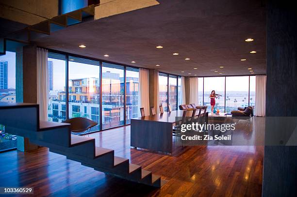 woman playing violin in modern condo living room - san diego homes stock pictures, royalty-free photos & images