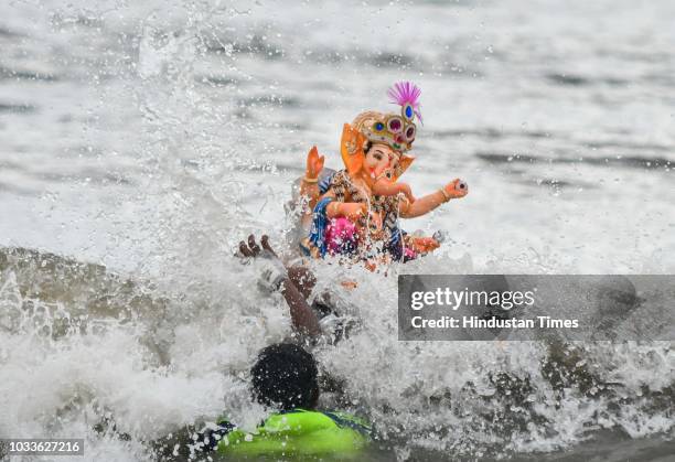 People carry and immerse the idols of Hindu God Ganesha on the first day of Ganpati Visarjan at Versova Beach, on September 14, 2018 in Mumbai,...