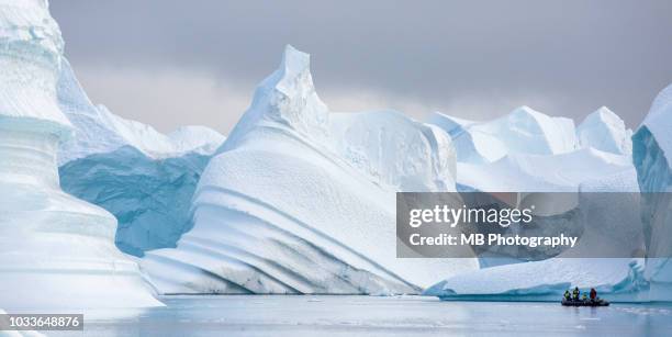 magnificent icebergs with zodiac boat. - grönland stock-fotos und bilder