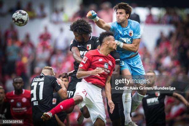 Goalkeeper Fabian Giefer of Augsburg clears the ball ahead of team mate Caiuby and Karim Onisiwo of Mainz during the Bundesliga match between 1. FSV...