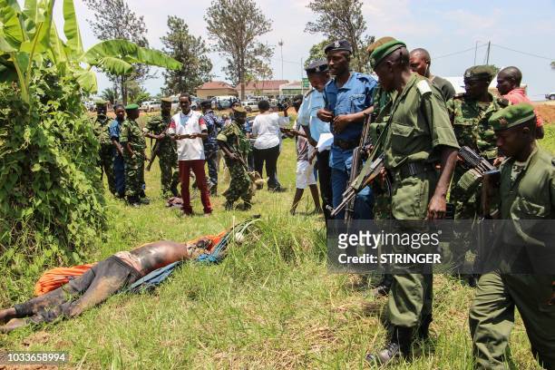 Burundi's police officers stand near a shot dead body of an alleged member of a rebel group from the neighboring Democratic Republic of Congo at the...