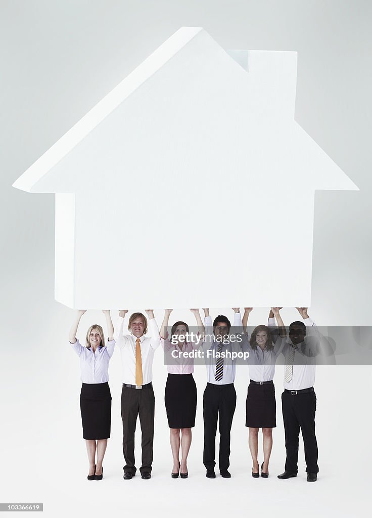 Business people holding up a house