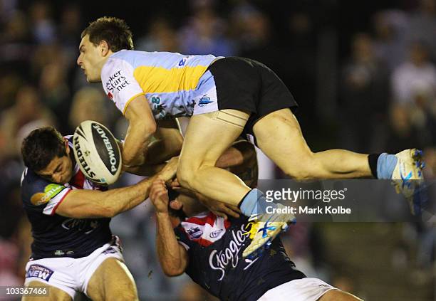 Nathan Gardner of the Sharks is tackled in the air by Anthony Minichiello and Braith Anasta of the Roosters during the round 23 NRL match between the...