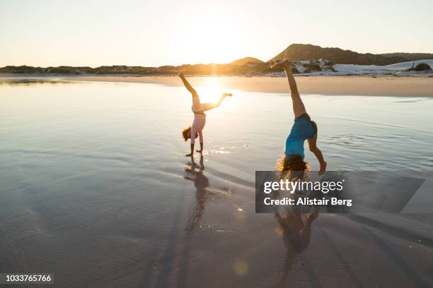 children playing on a beach at sunset - cartwheel stock pictures, royalty-free photos & images