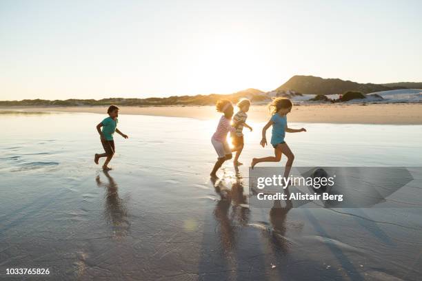 children playing soccer on a beach at sunset - barefeet soccer stock pictures, royalty-free photos & images