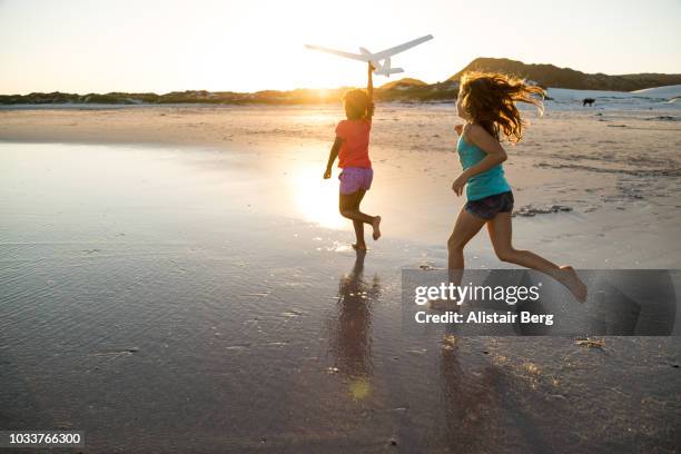 children playing on a beach at sunset - children playing silhouette stock pictures, royalty-free photos & images