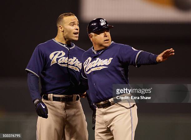 Scott Hairston of the San Diego Padres is held back by first base coach Rick Renteria after Hairston was called out for interference against the San...
