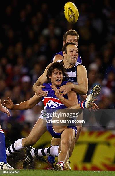 Ryan Griffen of the Bulldogs kicks whilst being tackled by Brad Ottens of the Cats during the round 20 AFL match between the Western Bulldogs and the...