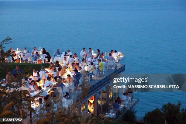 people dining outdoors in a restaurant overlooking the sea at sunset - dining overlooking water stock-fotos und bilder