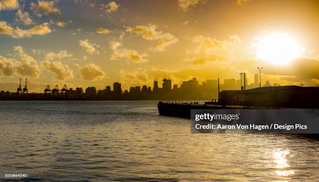 Skyline of Vancouver and the coastline with a golden sky at sunrise