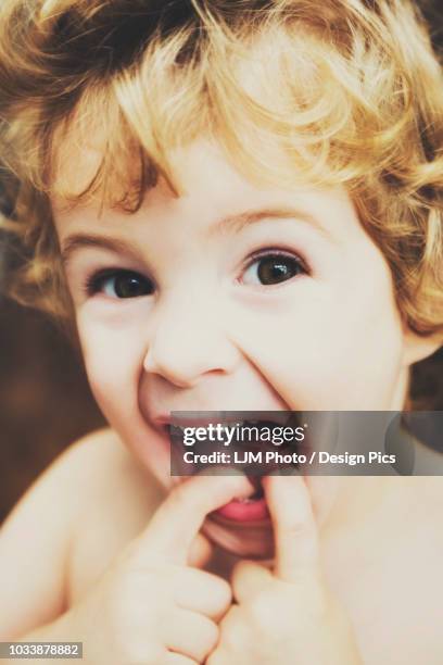 toddler making funny faces at the camera and putting his fingers in his mouth - kid putting finger in mouth photos et images de collection