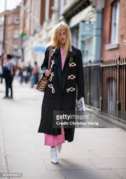 Ada Kokosar wearing black wool coat, pink skirt is seen outside JW Anderson during London Fashion Week September 2018 on September 15, 2018 in...