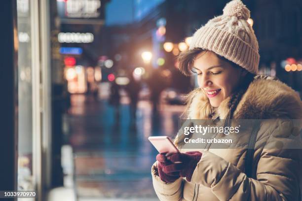 woman using phone in the winter - woman snow outside night stock pictures, royalty-free photos & images