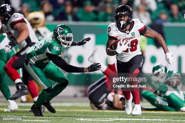 William Powell of the Ottawa Redblacks runs past Loucheiz Purifoy of the Saskatchewan Roughriders on his way to a touchdown in the game between the...