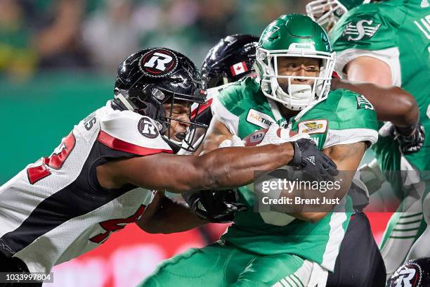 Marcus Thigpen of the Saskatchewan Roughriders is tackled by Avery Williams of the Ottawa Redblacks in the game between the Ottawa Redblacks and...