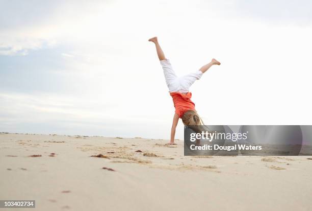 girl doing cartwheel at beach. - handstand beach photos et images de collection