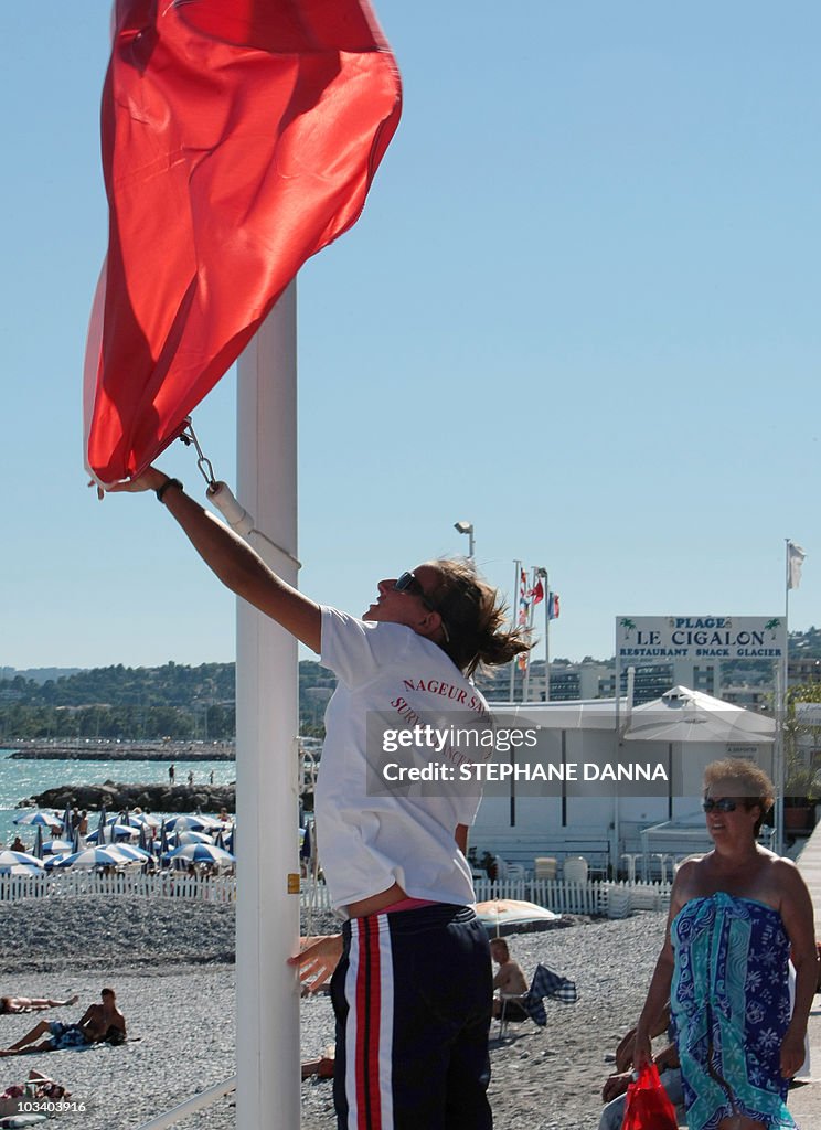 A French lifeguard raises the red flag t