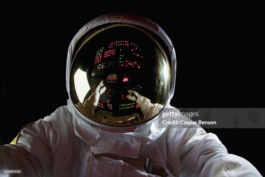 An astronaut in space making adjustments to a control panel