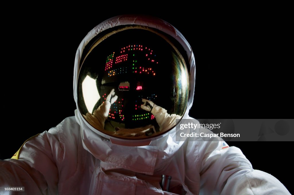An astronaut in space making adjustments to a control panel