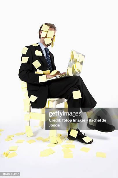 a man covered in blank adhesive notes while sitting and using a laptop - covered in post it notes stock pictures, royalty-free photos & images
