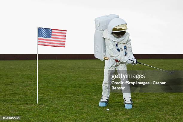 an astronaut swinging a golf club next to an american flag - golf humor stock pictures, royalty-free photos & images