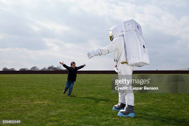 a boy running to meet his astronaut father with his arms outstretched - american flag on stand stock pictures, royalty-free photos & images