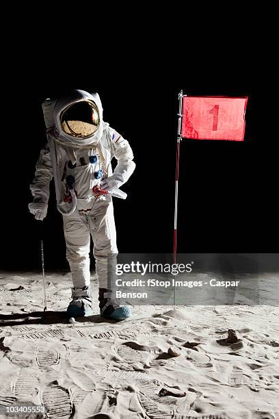 an astronaut on the moon standing next to number 1 hole flag - all flags stock-fotos und bilder