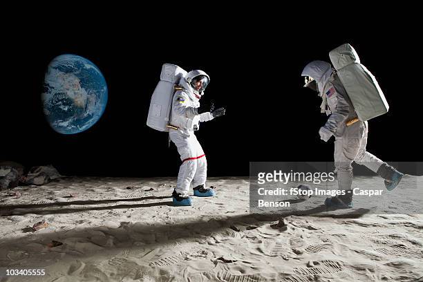 two astronauts playing soccer on the moon - astronaut mond stock-fotos und bilder