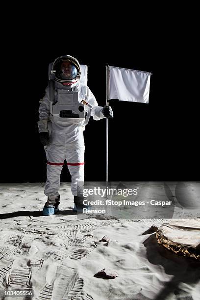 an astronaut standing next to a white flag - lunar stock-fotos und bilder